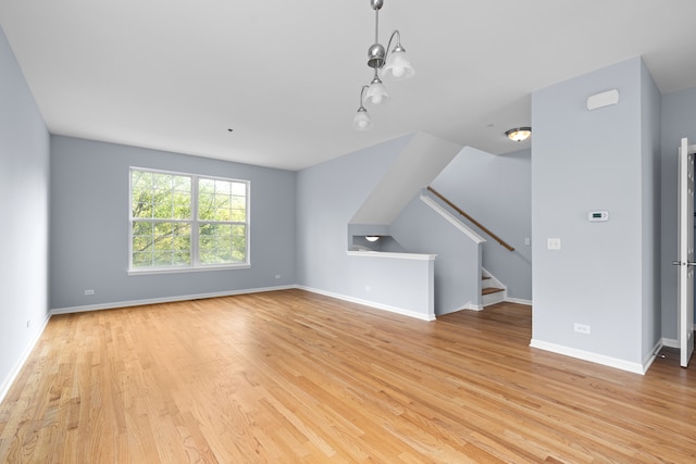 bonus room with light wood-type flooring and an inviting chandelier