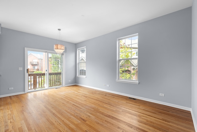 unfurnished room featuring hardwood / wood-style floors, plenty of natural light, and a chandelier