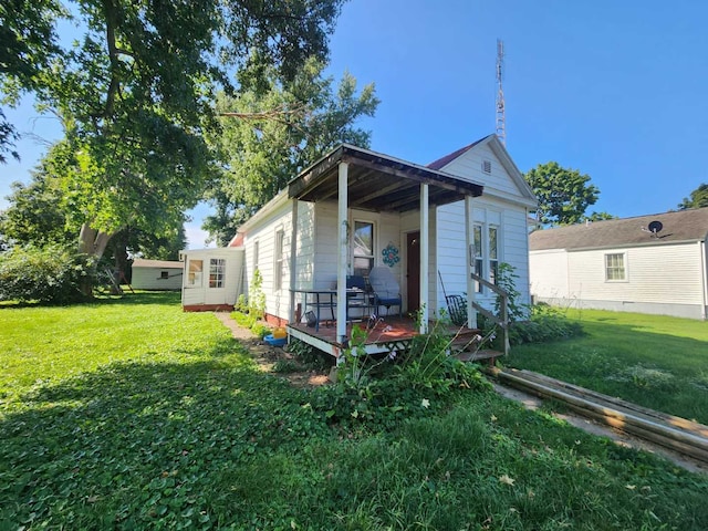 back of house with a lawn and covered porch