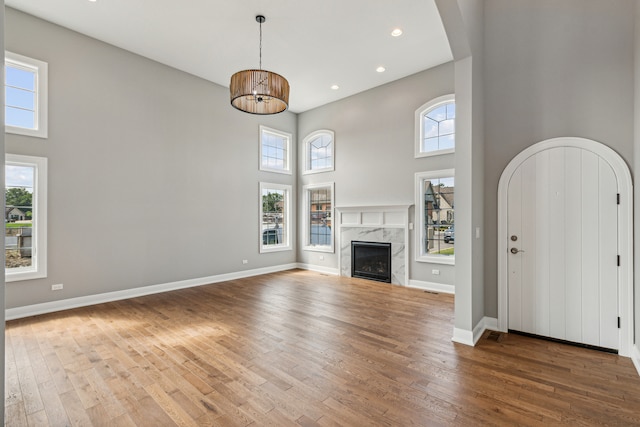 unfurnished living room featuring a fireplace, hardwood / wood-style floors, and a towering ceiling