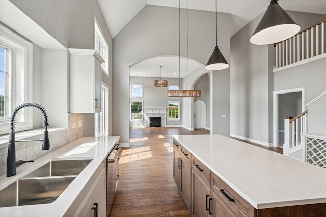 kitchen featuring high vaulted ceiling, a kitchen island, sink, and hardwood / wood-style flooring