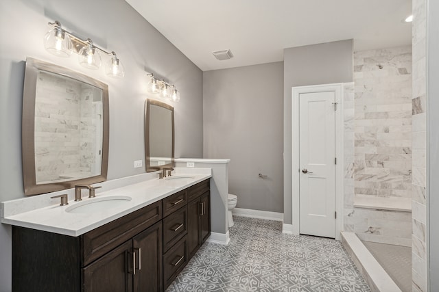 bathroom featuring tile patterned floors, vanity, toilet, and tiled shower