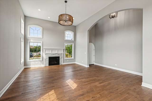 unfurnished living room with a premium fireplace, dark wood-type flooring, and a high ceiling