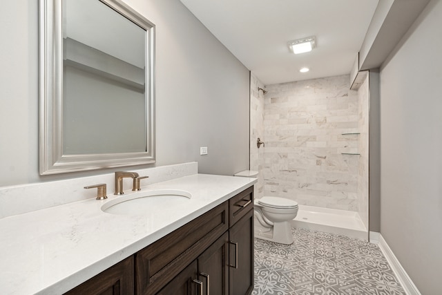 bathroom featuring a tile shower, vanity, tile patterned floors, and toilet