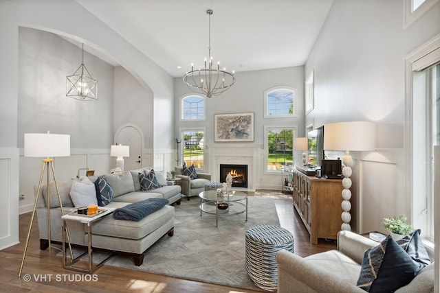 living room with a high ceiling, an inviting chandelier, and wood-type flooring