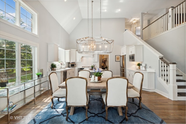 dining room with dark hardwood / wood-style flooring, a chandelier, sink, and high vaulted ceiling