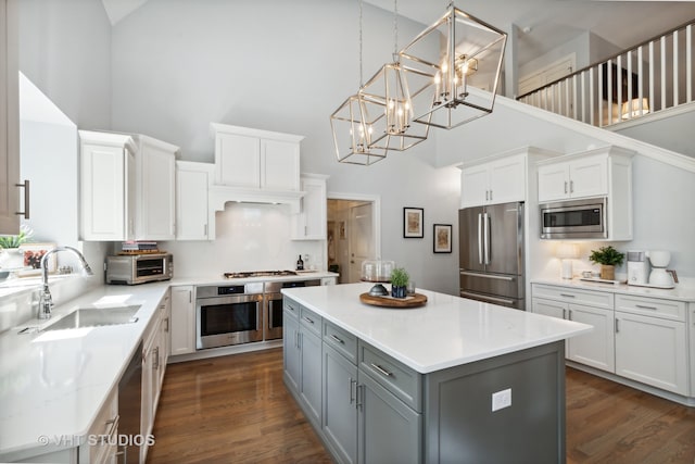 kitchen featuring a high ceiling, appliances with stainless steel finishes, sink, and white cabinets