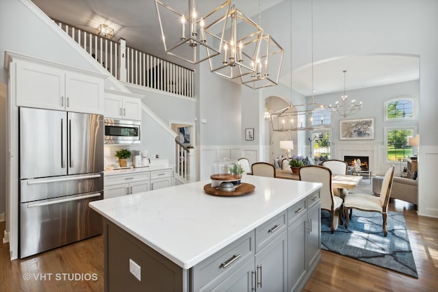 kitchen featuring a high ceiling, dark wood-type flooring, decorative light fixtures, and stainless steel appliances