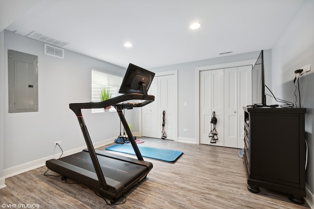 workout area with electric panel and hardwood / wood-style floors