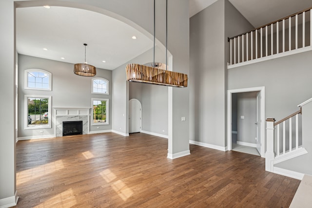 unfurnished living room with a towering ceiling, a premium fireplace, and hardwood / wood-style flooring