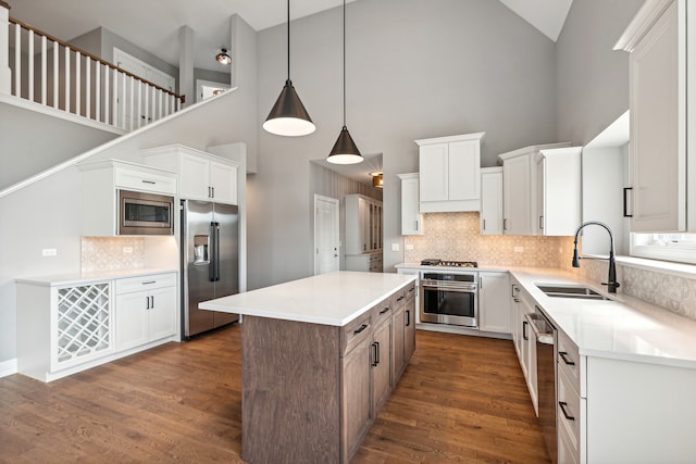 kitchen with white cabinets, high vaulted ceiling, stainless steel appliances, and sink