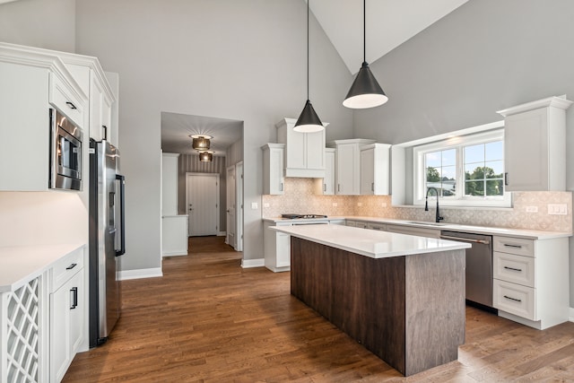 kitchen with white cabinets, high vaulted ceiling, appliances with stainless steel finishes, and a kitchen island