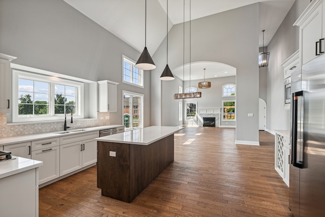 kitchen featuring high vaulted ceiling, built in refrigerator, white cabinetry, and a center island