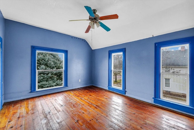 empty room with a healthy amount of sunlight, wood-type flooring, and vaulted ceiling