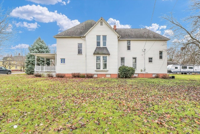 back of property featuring a yard and covered porch