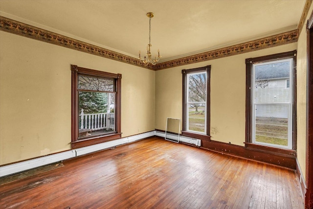 unfurnished room featuring a chandelier, wood-type flooring, plenty of natural light, and ornamental molding