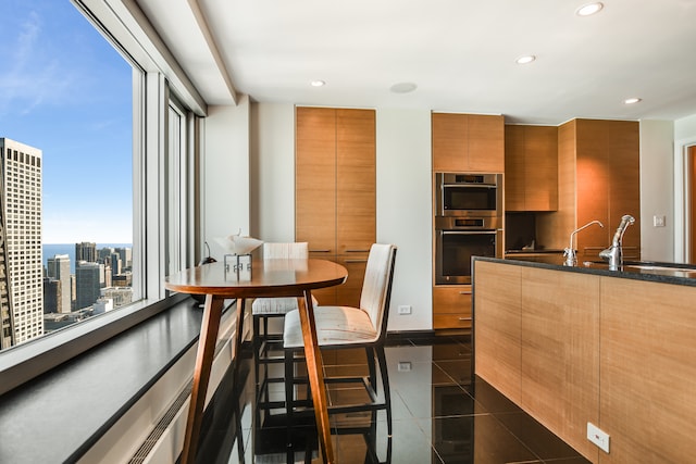 kitchen with a healthy amount of sunlight, sink, dark tile patterned floors, and double oven