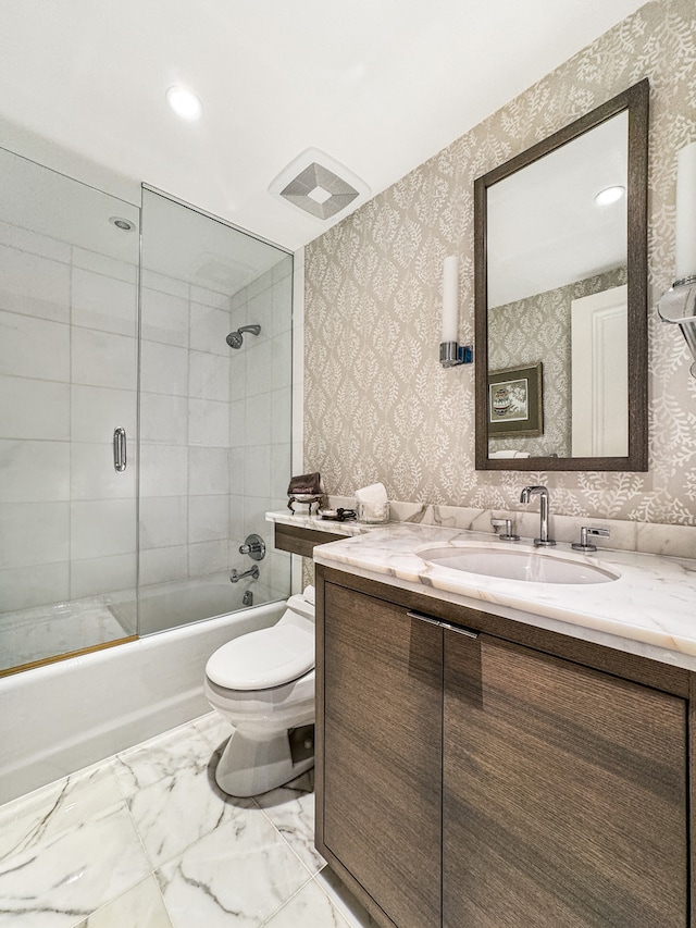 full bathroom featuring toilet, combined bath / shower with glass door, and vanity