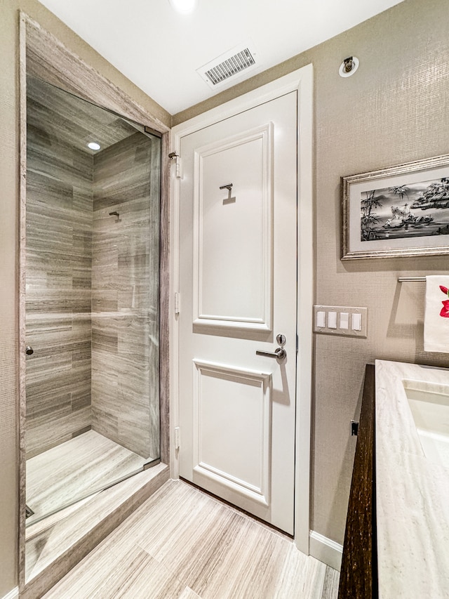 bathroom featuring vanity, a tile shower, and hardwood / wood-style floors