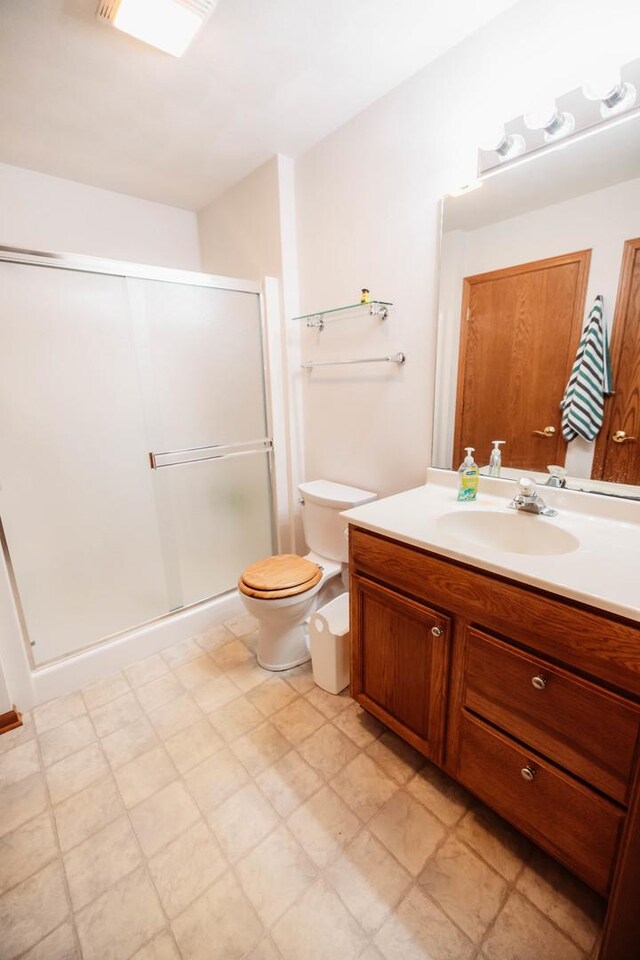 bathroom featuring walk in shower, toilet, and vanity