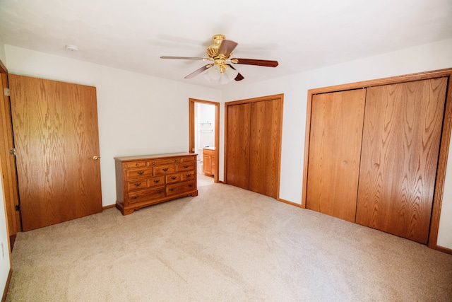 unfurnished bedroom with light carpet, two closets, ceiling fan, and ensuite bathroom