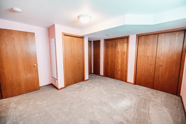 unfurnished bedroom with light colored carpet and multiple closets