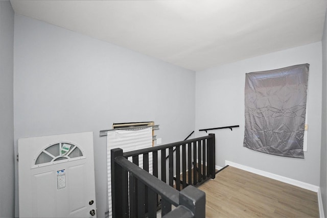 hallway with an upstairs landing and wood finished floors
