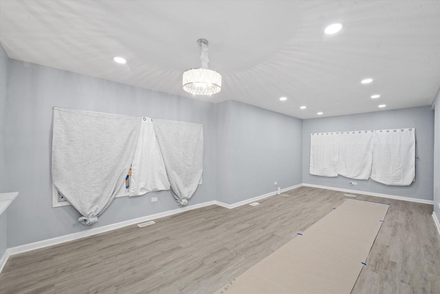 spare room with wood finished floors, a chandelier, and recessed lighting