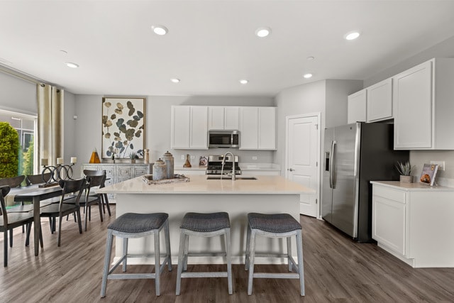 kitchen featuring dark wood-type flooring, a breakfast bar area, sink, and appliances with stainless steel finishes