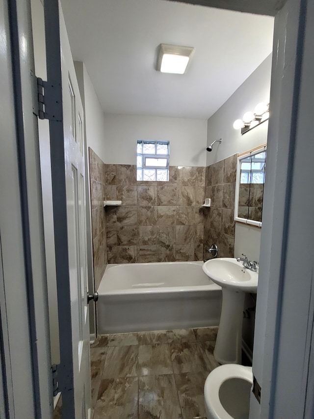 bathroom with toilet and tiled shower / bath combo