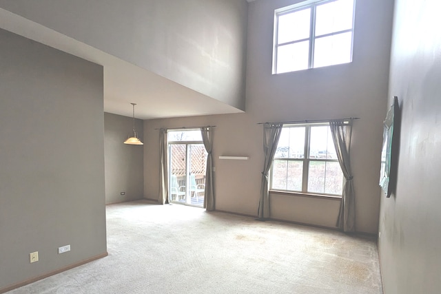 spare room featuring a towering ceiling and light colored carpet