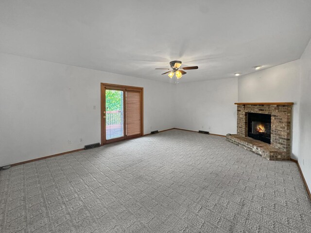 unfurnished living room featuring light colored carpet, a brick fireplace, and ceiling fan