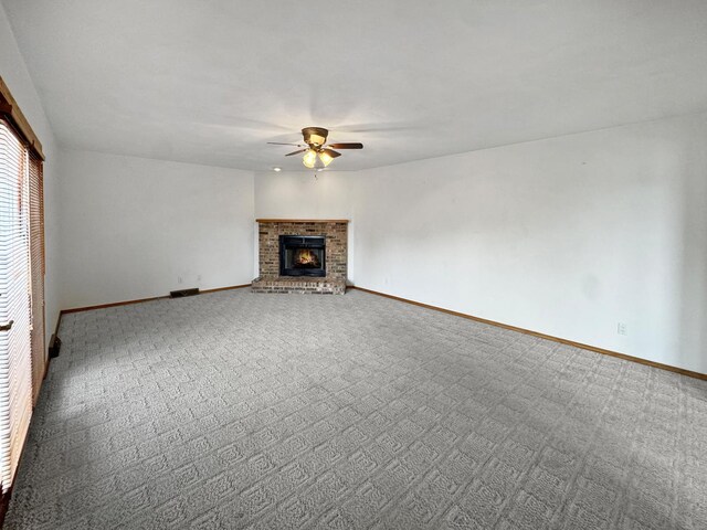 unfurnished living room with ceiling fan, carpet floors, and a brick fireplace