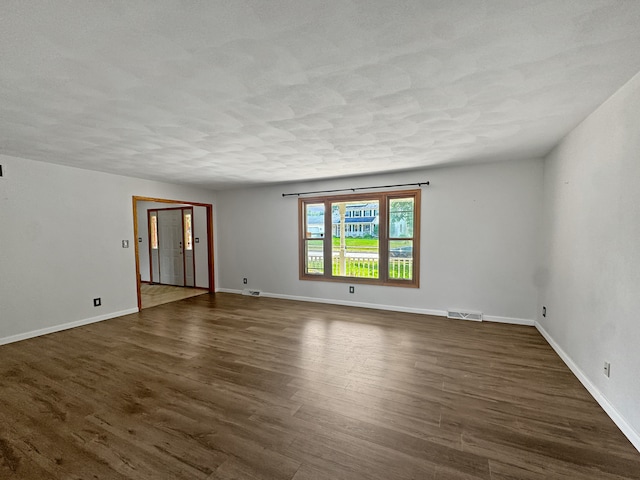 empty room with a textured ceiling and dark hardwood / wood-style flooring