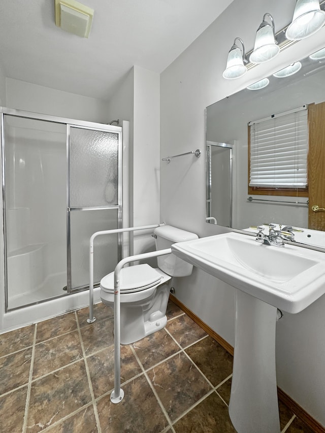 bathroom featuring toilet, sink, and a shower with door