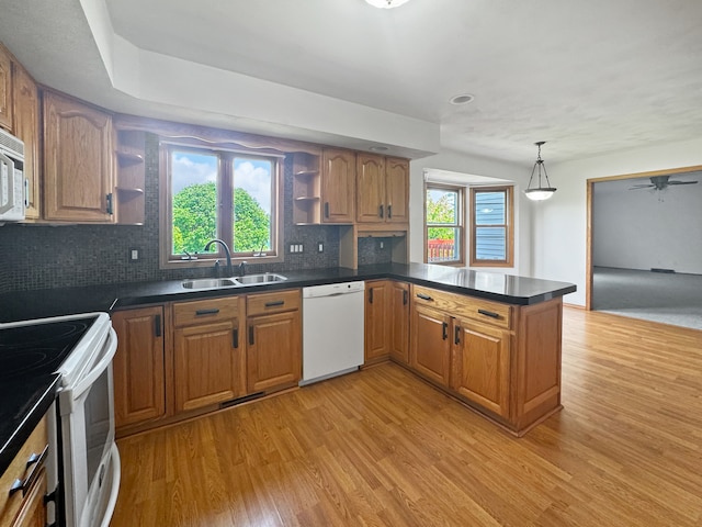 kitchen featuring a healthy amount of sunlight, white appliances, kitchen peninsula, and sink