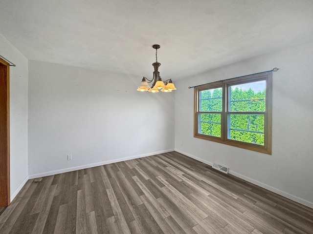 spare room featuring dark hardwood / wood-style floors and a notable chandelier