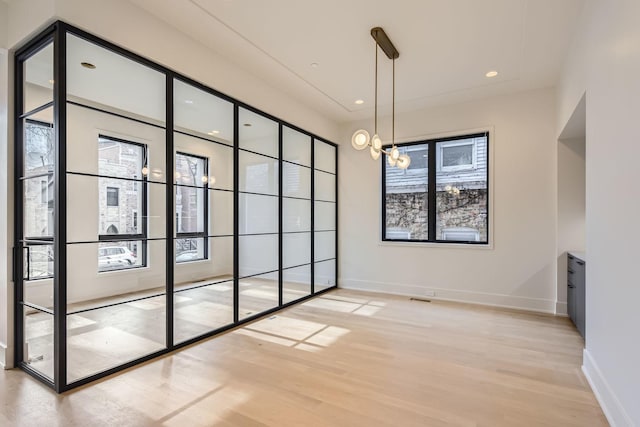 unfurnished dining area featuring a notable chandelier and light hardwood / wood-style flooring