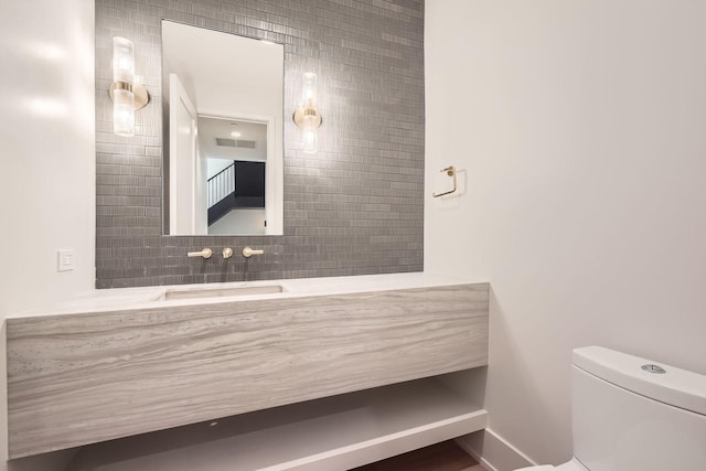 bathroom with vanity, toilet, and backsplash