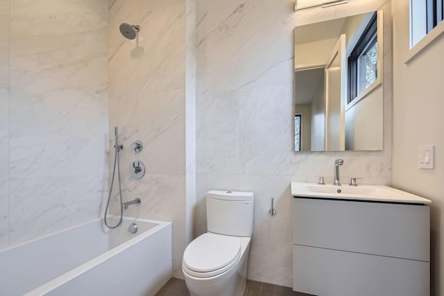 full bathroom with vanity, toilet, tiled shower / bath combo, and tile walls