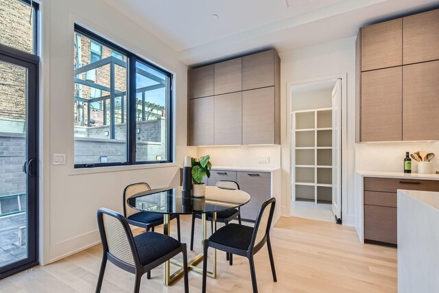 kitchen featuring sink, white cabinetry, light wood-type flooring, stainless steel microwave, and light stone countertops