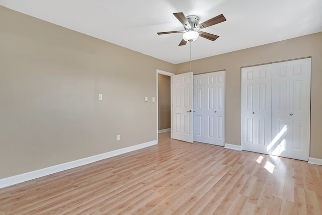 unfurnished bedroom featuring ceiling fan, multiple closets, and light hardwood / wood-style floors