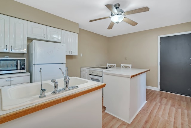 kitchen featuring light wood-type flooring, white appliances, white cabinetry, ceiling fan, and a kitchen island