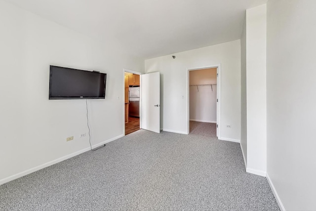 unfurnished bedroom with a walk in closet, stainless steel refrigerator, a closet, and carpet floors