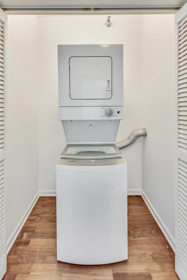 laundry room featuring light wood-type flooring and stacked washer / dryer