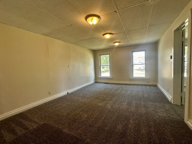 empty room featuring a drop ceiling and dark carpet