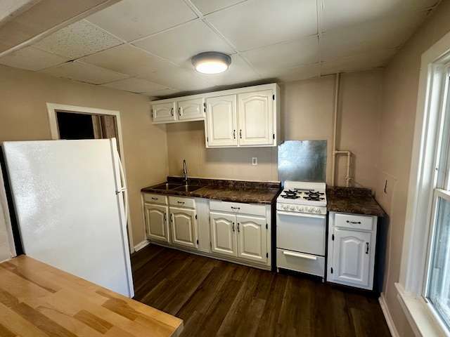 kitchen with white cabinets, sink, white appliances, a drop ceiling, and dark hardwood / wood-style floors