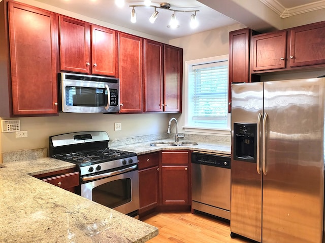 kitchen with crown molding, appliances with stainless steel finishes, light stone countertops, light hardwood / wood-style floors, and sink