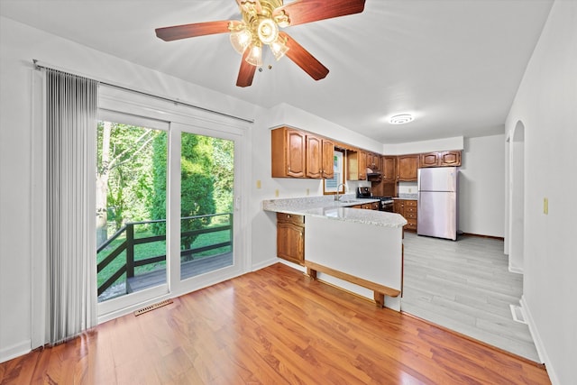 kitchen featuring appliances with stainless steel finishes, a wealth of natural light, ceiling fan, and light hardwood / wood-style floors