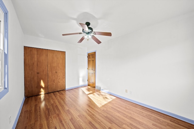 unfurnished bedroom featuring hardwood / wood-style flooring, ceiling fan, and a closet